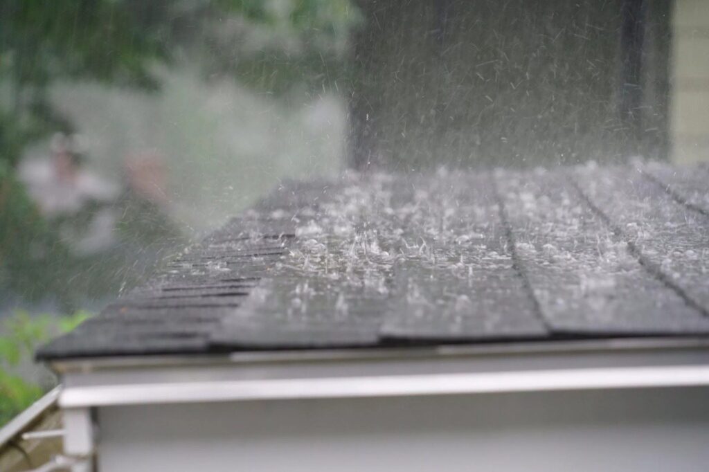 Rain and hail hitting impact resistant shingles on residential roof in Virginia